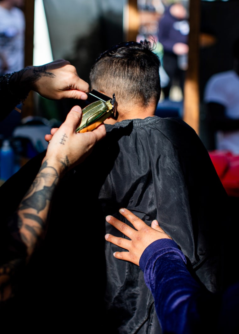 A barber at the Altadena Teen Boys Fire Recovery event cuts the hair of a boy whose family was displaced by the Eaton Fire.