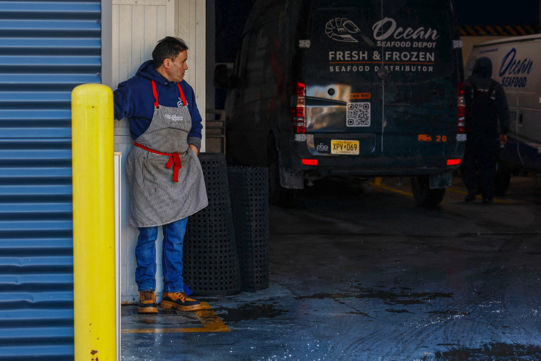 A worker stands at the parking area of the Ocean Seafood Depot .