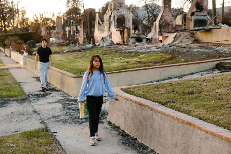 Siblings Sam and Colette walk down their Altadena street, passing by the ruins of their home and their neighbors’ homes. 