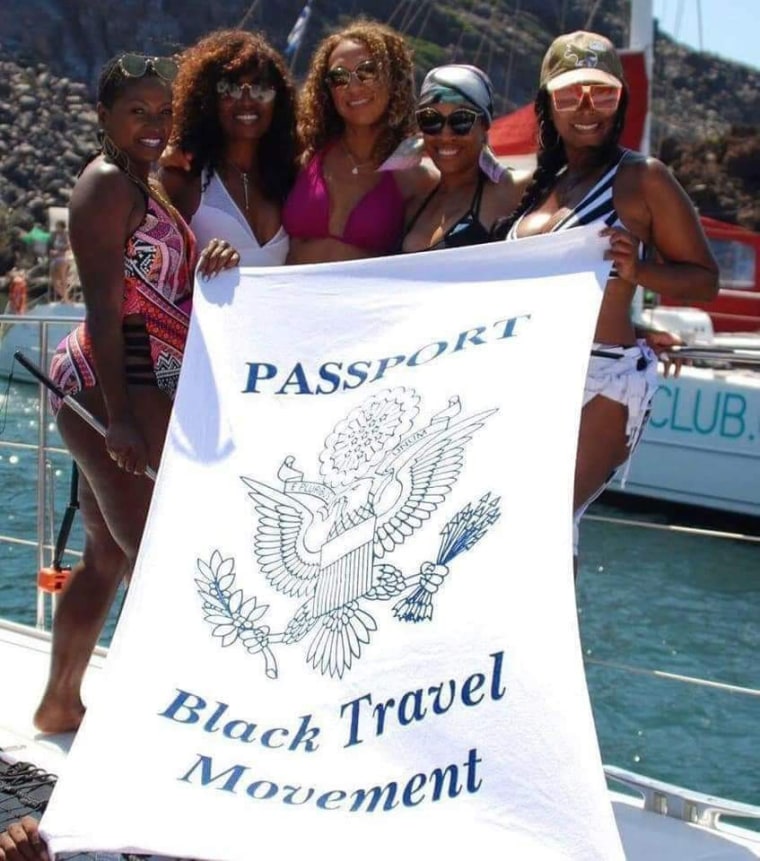 Travelers on a yacht posing with a Black Travel Movement towel.