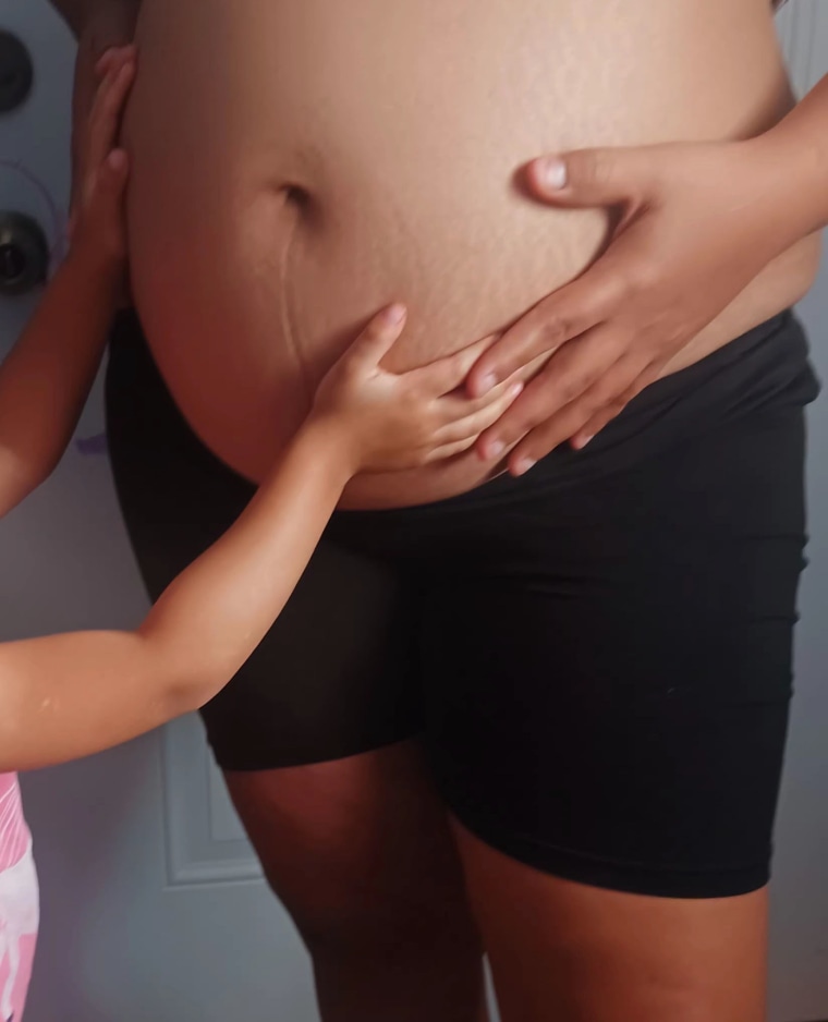 Nivida's U.S.-born first child touches her belly.