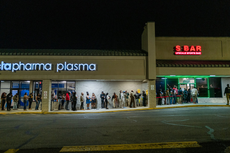 A line of people wait outside of S Bar