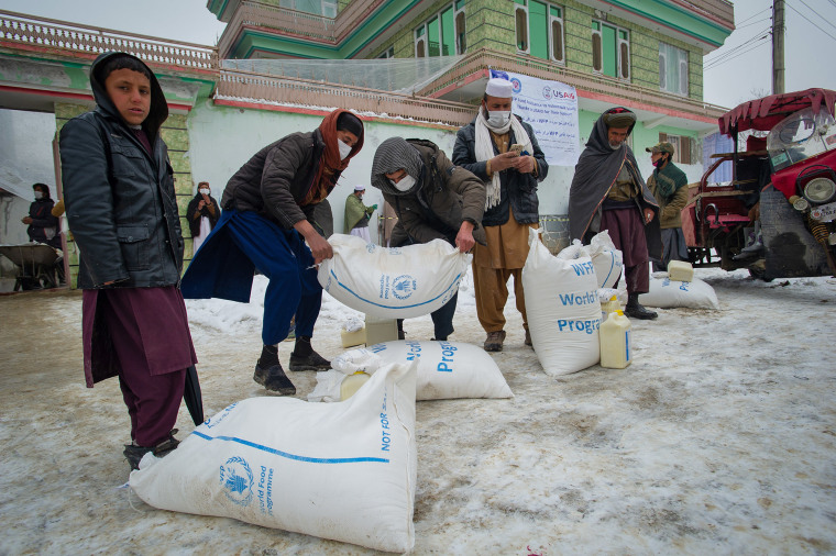 Afghan men prepare to transport sacks of flour as the U.N. World Food Program distributes a critical monthly food ration, with food largely supplied by USAID, south of Kabul in 2022.