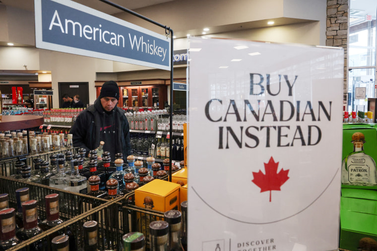 Los estantes vacíos permanecen con letreros '' comprar canadiense en su lugar '' después de que las cinco mejores marcas de licor de EE. UU. Se retiraran de la venta en una licorería BC, en Vancouver