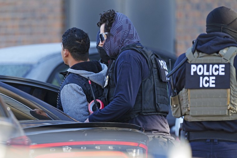 Law officials escort a suspect during a raid of an apartment complex in Denver. 