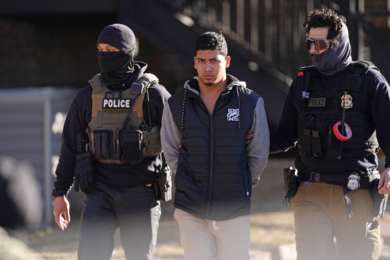 Law officials escort a suspect from an apartment during a raid in Denver. 