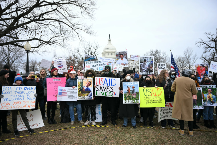 People hold signs in protest in front of the Capitol building