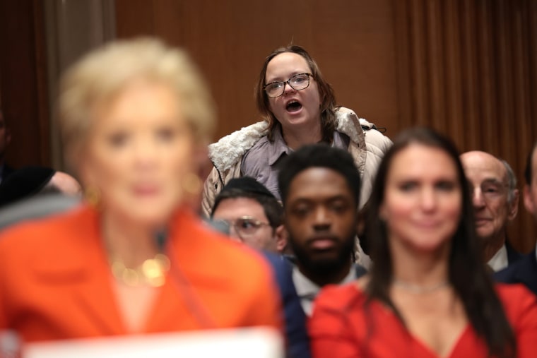 A protester disrupts Linda McMahon as she testifies during her Senate Health, Education, Labor and Pensions Committee confirmation hearing on Feb. 13, 2025.