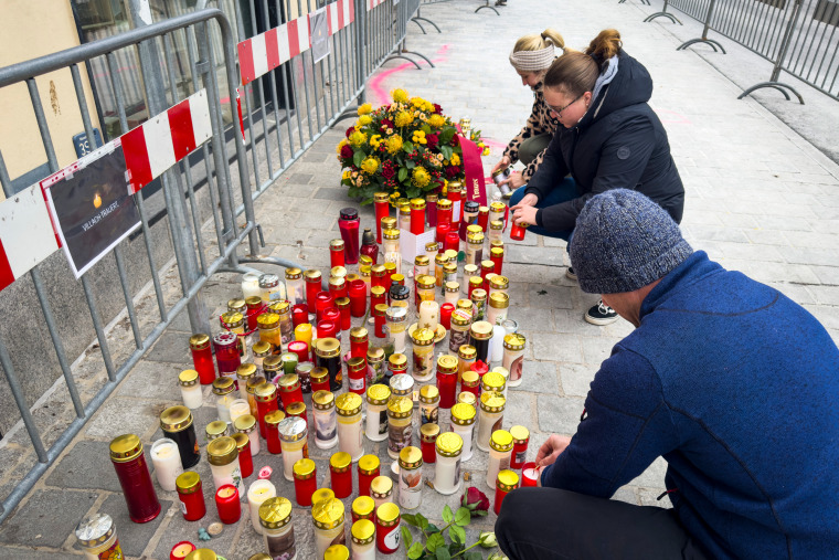 People light candles on a sidewalk