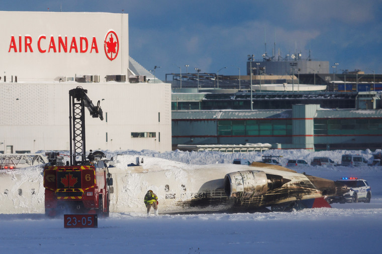 Emergency responders work around an aircraft on a runway, after a plane crash at Toronto Pearson International Airport in Mississauga