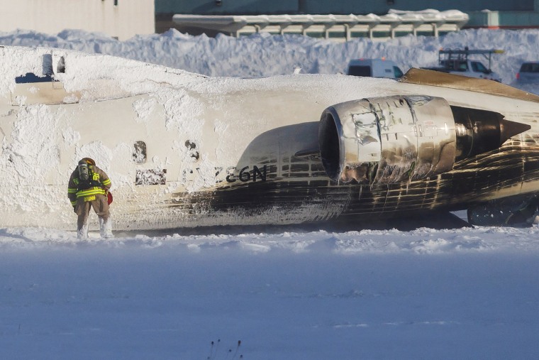 Emergency responders work around an aircraft on a runway, after a plane crash at Toronto Pearson International Airport in Mississauga