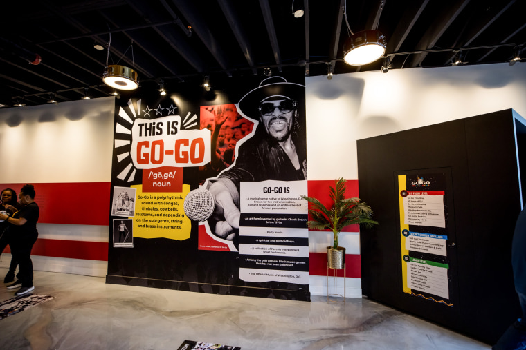 A museum wall with text that reads "This is Go-Go" and an image of a man holding a microphone