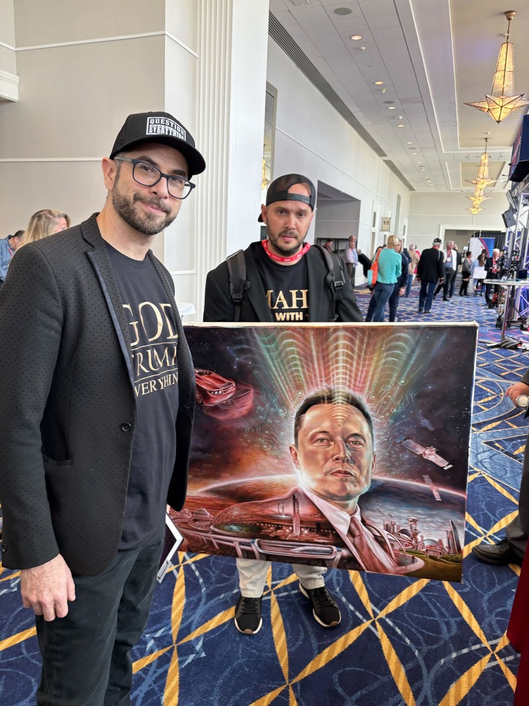 Seth Libywitz stands to the left, next to the Elon Musk painting that musk caught on the stage after his speech in CPAC.