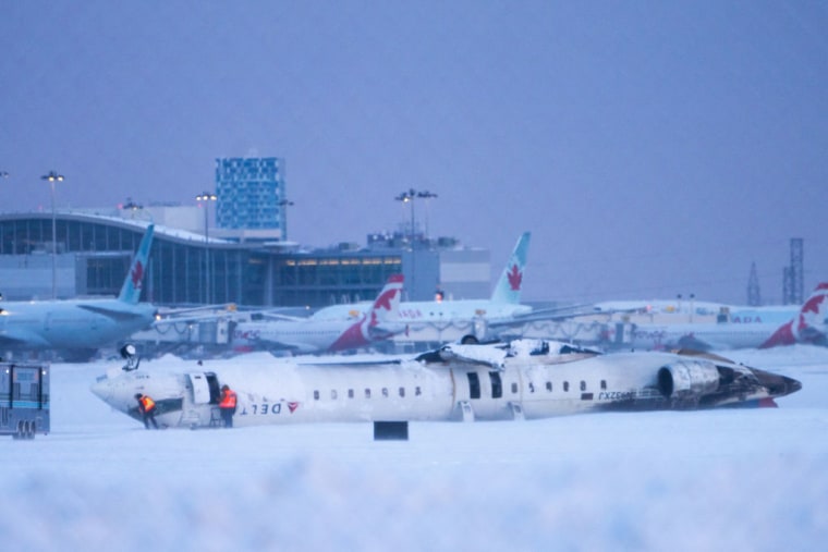 Trabajadores del aeropuerto inspeccionan el lugar del accidente de un avión de Delta Air Lines en el Aeropuerto Internacional Toronto Pearson, el 18 de febrero de 2025, en Toronto, Canadá. 