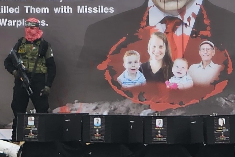 A Hamas militant stands on a stage with the coffins of what it said were the four deceased Israeli hostages it handed over to the Red Cross on Thursday.