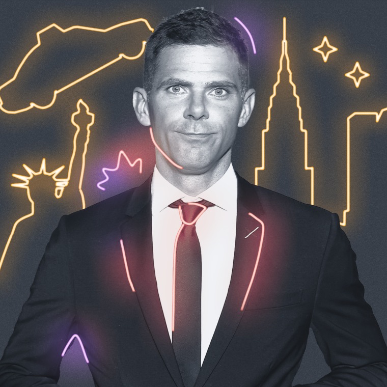 Mikey Day with yellow neon signs behind them on a gray background