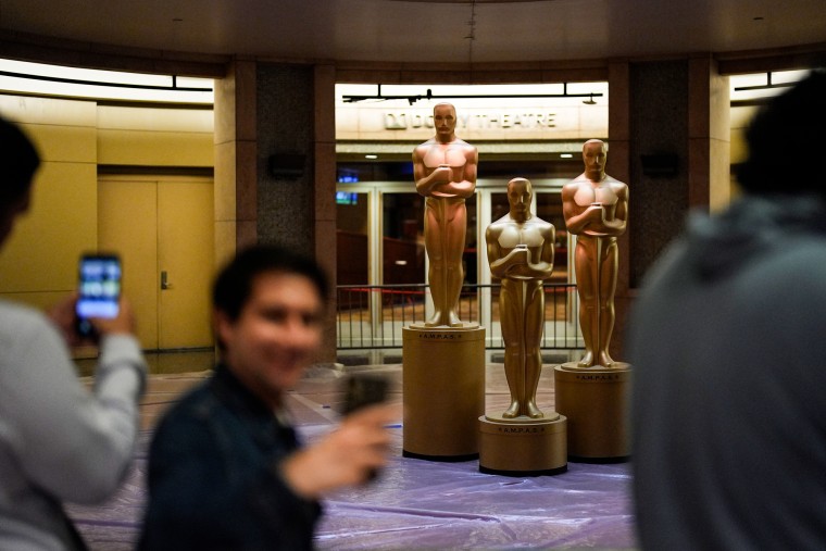 People take selfies in front of large Oscar statues