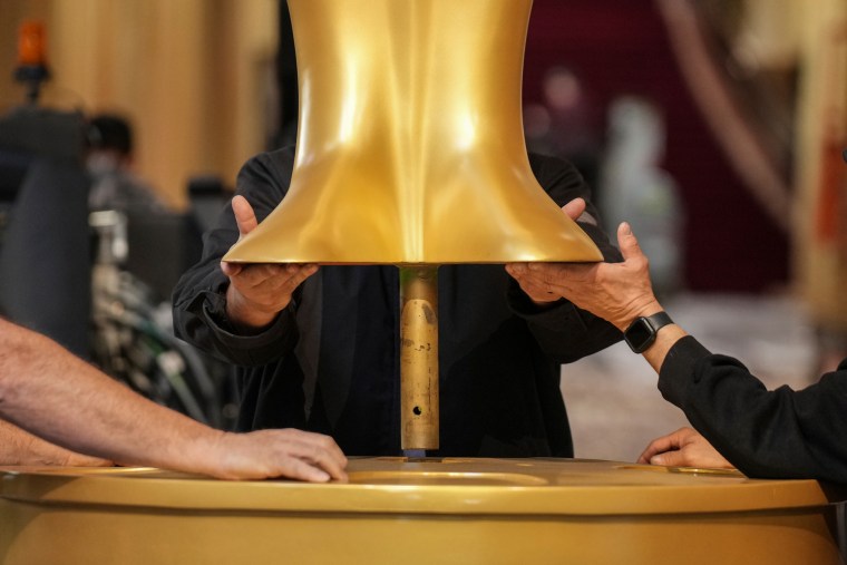 Hands lower the bottom of a statue onto a post