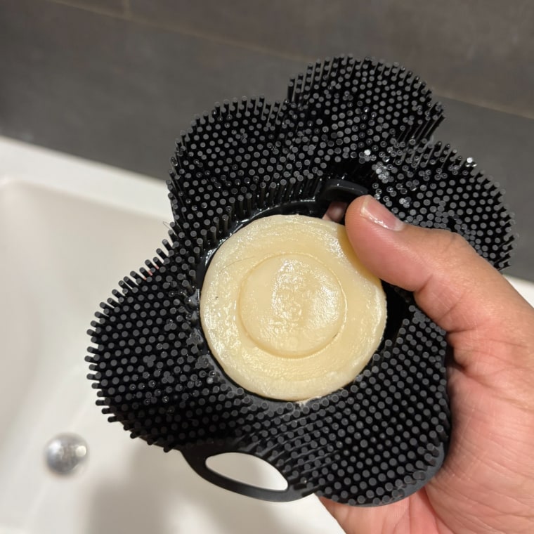 Person holding shave bar in Smoosh silicone body scrubber.