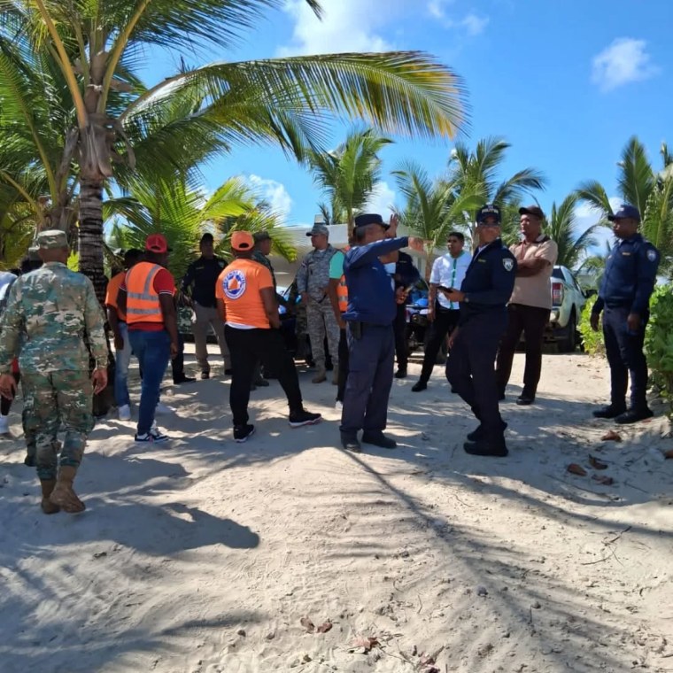 People gather in a group to search on a beach