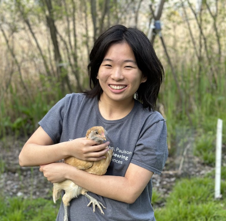 Christina Yi holds a chicken while smiling outside