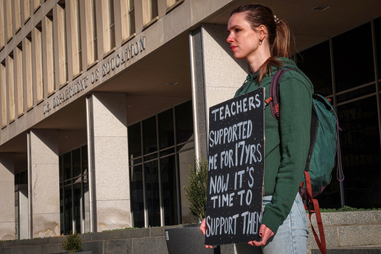 A person holds a sign outside of DOD.