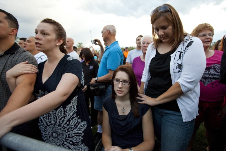 Anne Marie Hochhalter, 30, bottom, and her friend Roxy Chesser, 30, second from right, attend a prayer vigil, held to remember the lost and injured in a mass shooting at a movie theater, in Aurora, Colo., July 22, 2012.