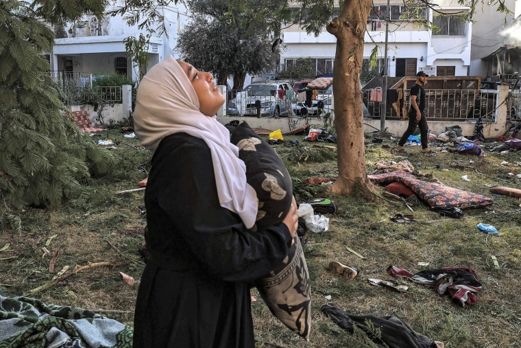 A woman stands amid debris outside the site of the Ahli Arab hospital in Gaza City on Oct. 18, 2023 in the aftermath of an overnight strike there.