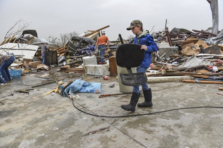 The boy helps to help a piece of family bris from a shop destroyed by an Arkansas tornado  