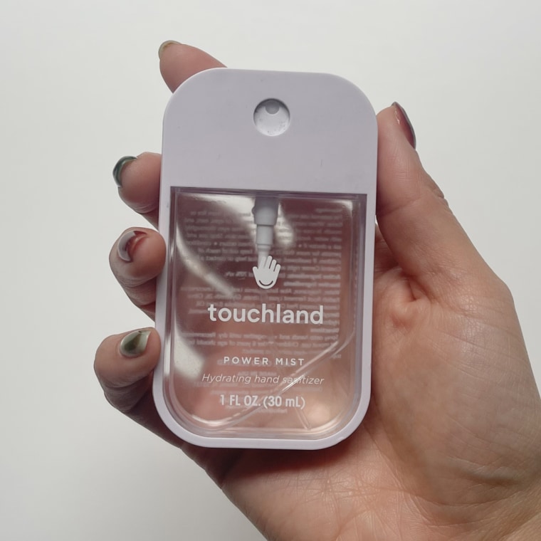 A woman holds a Touchland hand sanitizer in her hand.