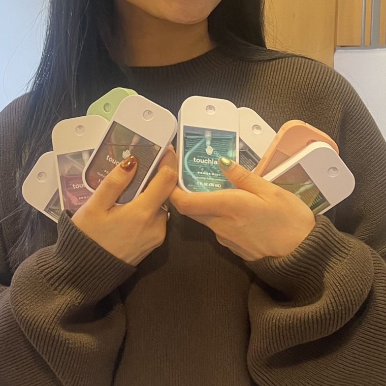 A woman holds eight Touchland hand sanitizers.