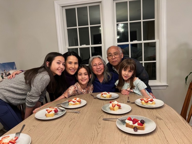 Photo of a family of six, seated around a dinner table.