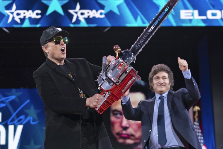 Elon Musk, left, receives a chainsaw from Argentina's President Javier Milei