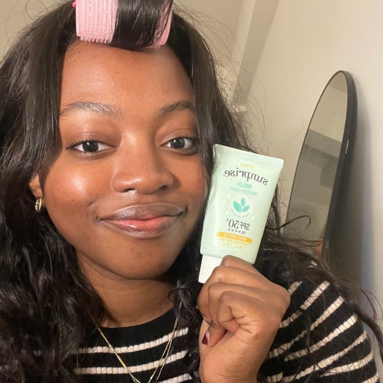 NBC Select editorial operations associate Jem Alabi holding up the Etude Sunprise Sun Milk beside her.