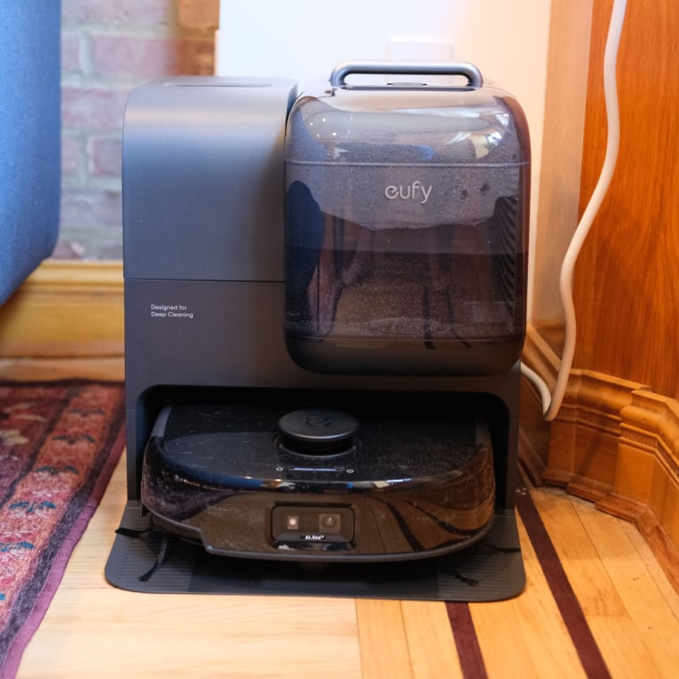 A close up of the Eufy Robot Vacuum Omni E28 in Rabinowitz’s home, set up in a corner on hardwood flooring.