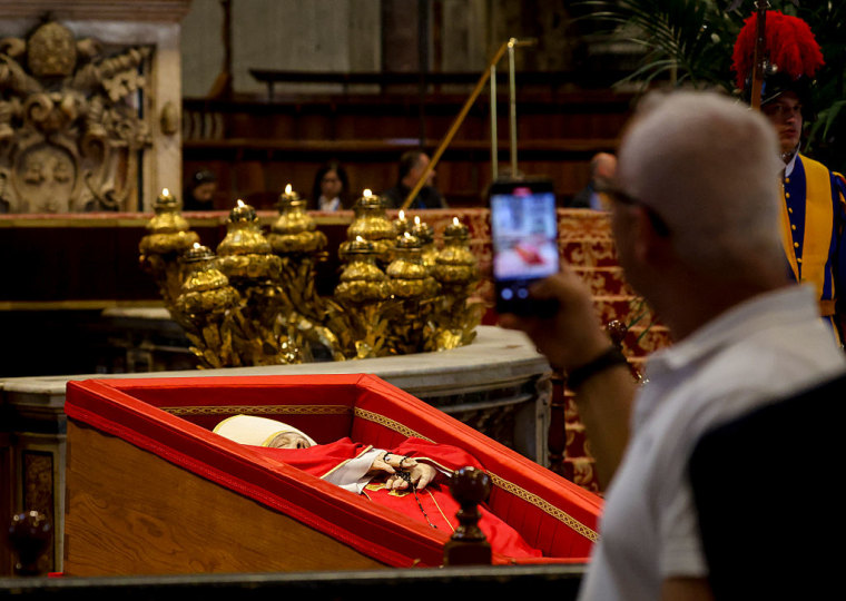Los fieles contemplan y fotografían el cuerpo del papa Francisco expuesto en el altar mayor.