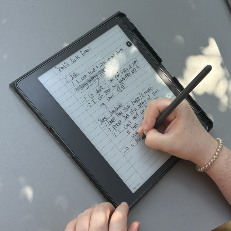 A close up image of someone holding a stylus to take notes on the Kindle Scribe.