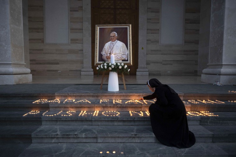 A Catholic nun lights a candle next to a portrait of the late Pope Francis displayed at the St. Mother Teresa Cathedral in Pristina on April 21, 2025. Pope Francis, an energetic reformer who inspired widespread devotion from Catholics but riled traditionalists, died on April 21, 2025 aged 88.