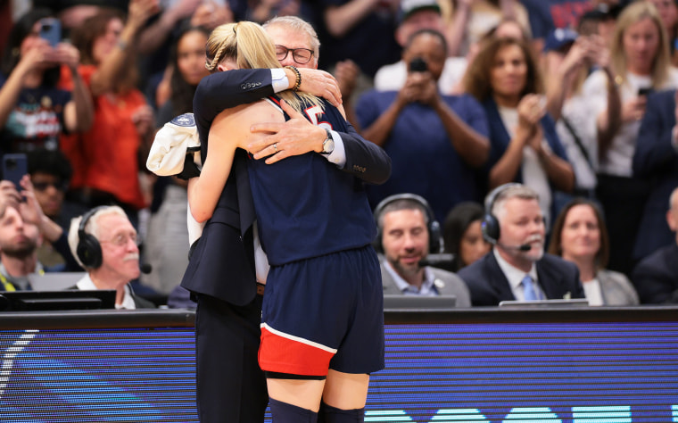 Paige Bueckers #5 of the UConn Huskies hugs head coach Geno Auriemma.