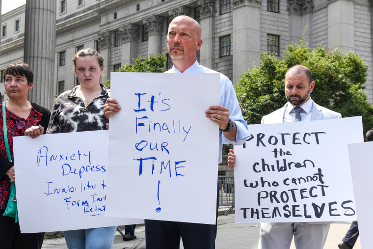 Patrick Noaker, center, holds a sign that says