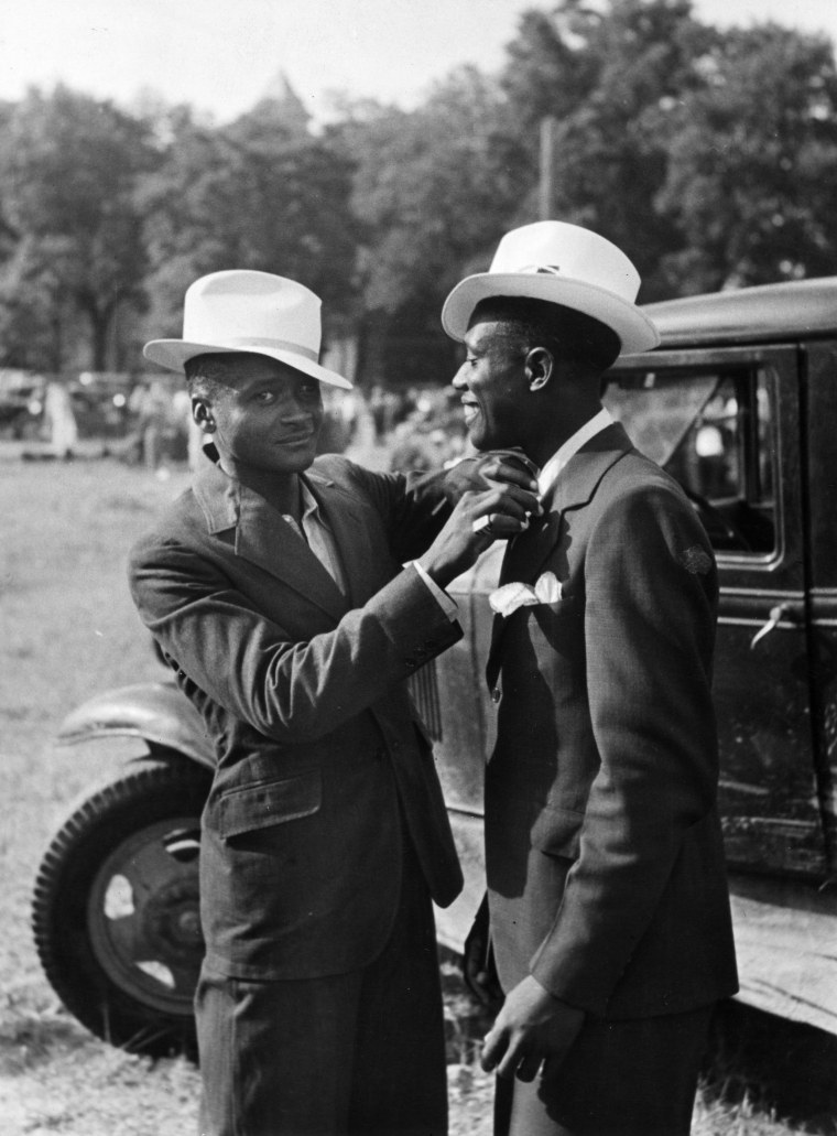 An man adjusting his friend's tie in Kansas City circa 1940.