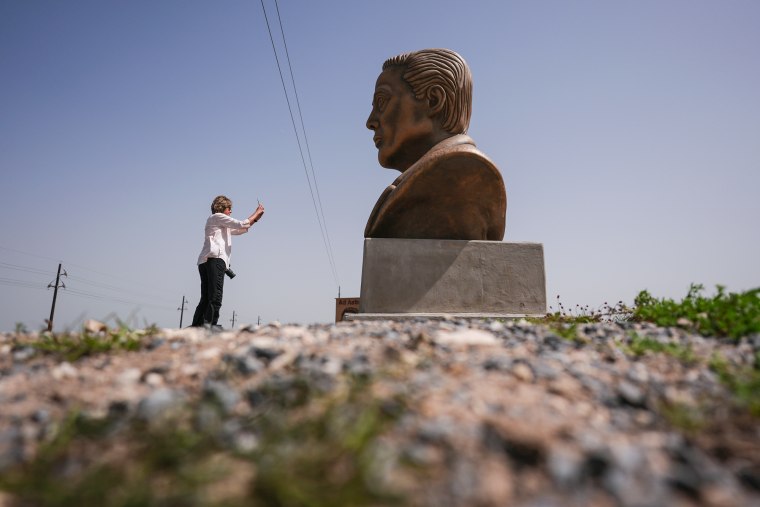 A visitor photographs a large bust of Elon Musk outside