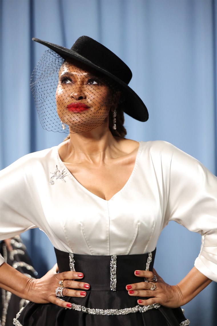 Ava DuVernay looks radiant in a cinched gown and black brimmed hat.