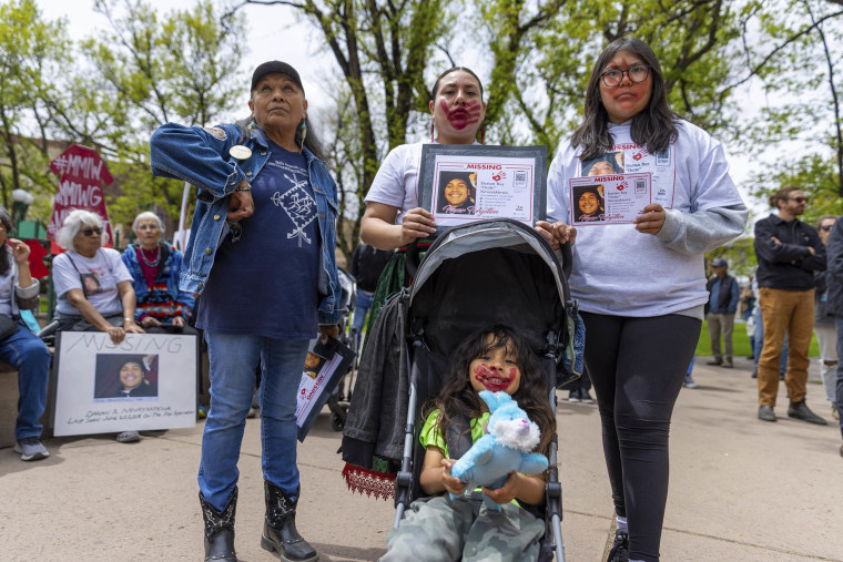 Three relatives of Darian Nevayaktewa holding signs up to raise awareness about his disappearance at a rally in Santa Fe