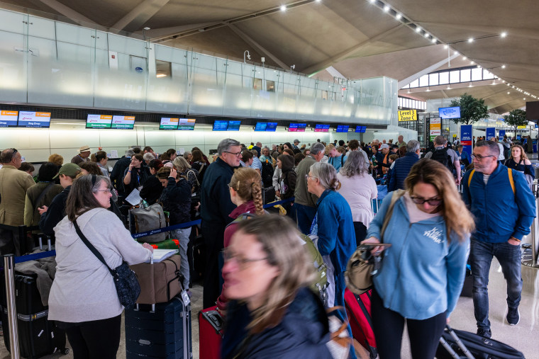 People wait in line for a delayed flight