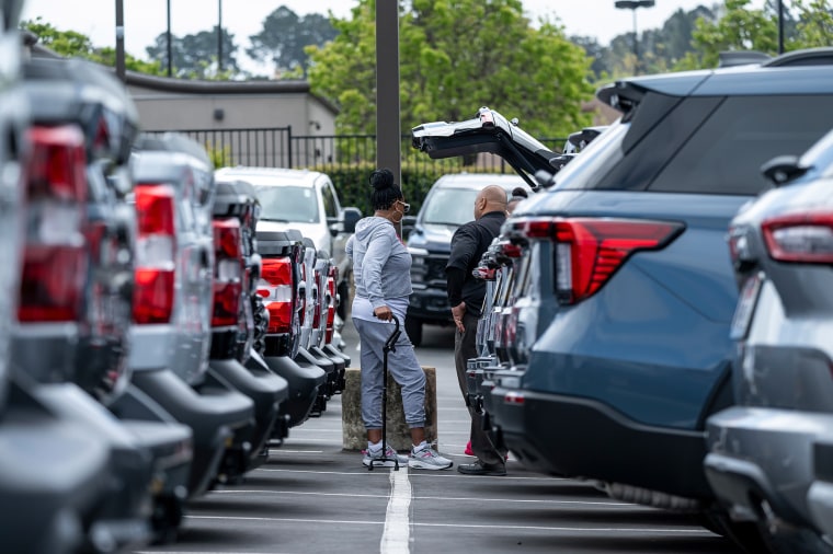 Customers are looking at the car at the dealer
