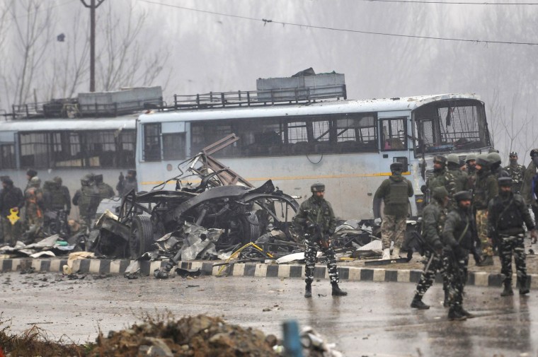 Security forces near the damaged vehicles at Lethpora on the Jammu-Srinagar highway.