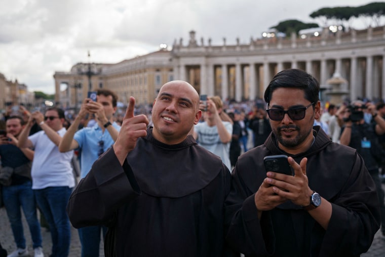 Priests stand on St Peter's Square after black smoke billowed from a chimney over the Sistine Chapel, on the second day of the conclave, in the Vatican on May 8, 2025.