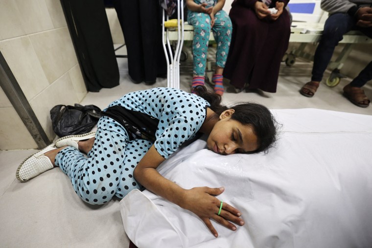 A Palestinian girl mourns over the shrouded body of her mother at a hospital in the Nuseirat refugee camp in central Gaza on May 7, 2025.