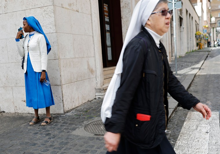 A nun from Nigeria speaks on the phone as another nun walks past on May 6, 2025 in Rome.